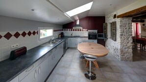 Eine moderne Küche mit einer zentralen Kochinsel, einem Essbereich mit einem Holztisch und einer Steinwand.
