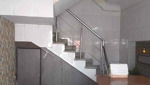 A modern interior with a staircase leading to a second floor, a kitchen area, and a seating area with a red couch. - Manbhar Heavens Hotel (Amer)