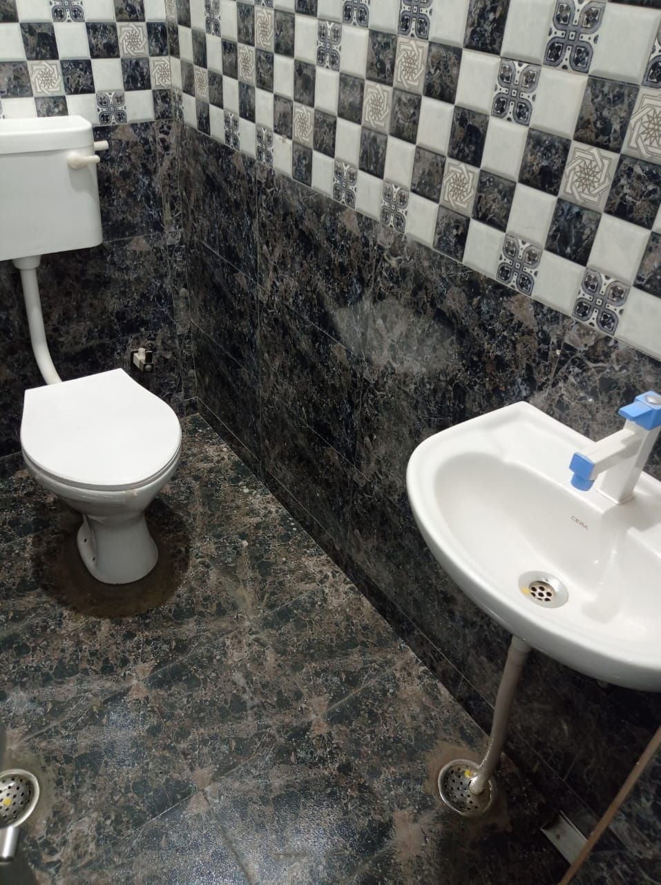 Une salle de bain avec des toilettes, un lavabo et un mur recouvert de carreaux.