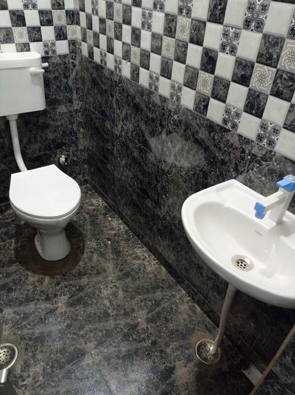 Un baño con inodoro, lavamanos y salpicadero de azulejos.