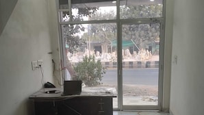 A room with a marble floor, a desk with a laptop, and a large window overlooking a street with statues and trees. - Manbhar Heavens Hotel (Amer)
