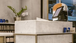 A reception desk with a marble top, a digital screen, and a gold frame. - Manbhar Heavens Hotel (Amer)