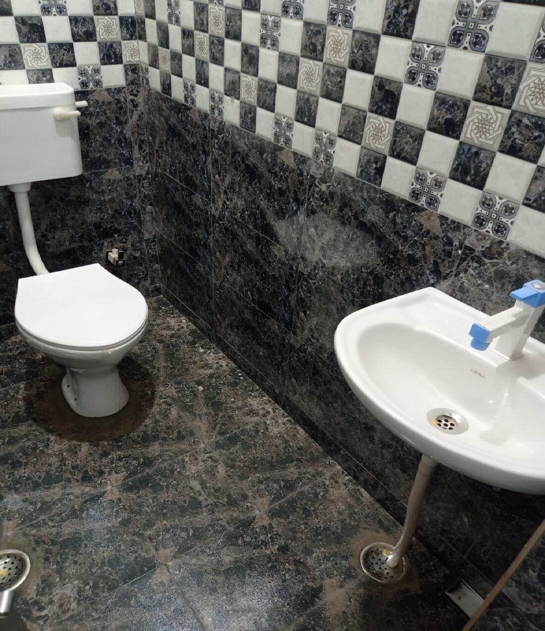 Un baño con inodoro, lavamanos y azulejos decorativos en las paredes.