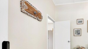 A hallway with a wooden floor, a white door, and a small table with decorative items.