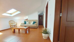Una sala de estar con un sofá, una silla de madera, una mesa de centro y una planta en maceta.