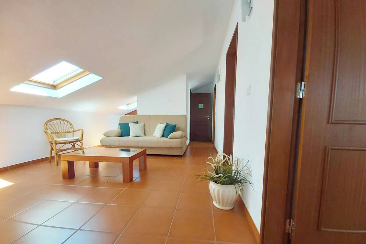 Una sala de estar con un sofá, una silla de madera, una mesa de centro y una planta en maceta.
