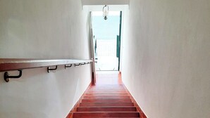 Una escalera con barandilla de metal que conduce a un espacio amplio y luminoso.