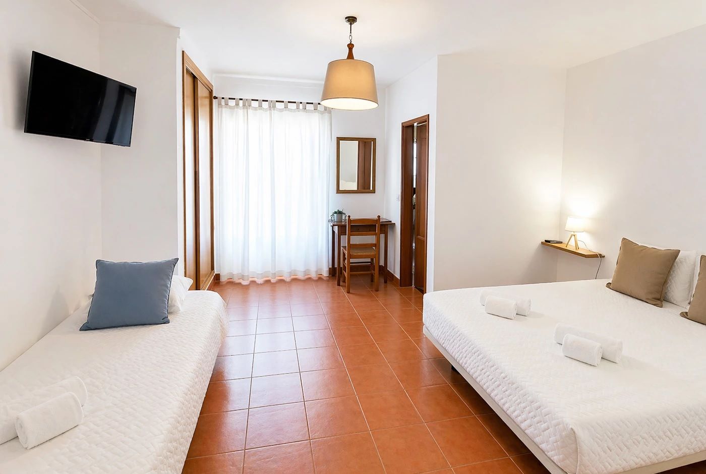 Une chambre d’hôtel avec deux lits, une télévision, un bureau et une chaise.