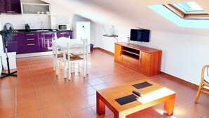 Un espacio habitable compacto con cocina, comedor y televisor.