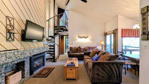 Ein gemütliches Wohnzimmer mit Kamin, einer Couch, einem Couchtisch und einem an der Wand befestigten Fernseher.