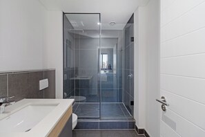 Ein modernes Badezimmer mit Duschkabine aus Glas, einem weißen Waschbecken und einer Toilette.