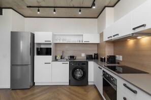 Eine moderne Küche mit einem Edelstahlkühlschrank, einer integrierten Waschmaschine und einer eleganten Arbeitsplatte.