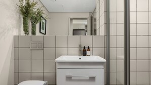 A modern bathroom with a white sink, two bottles of shampoo, and a toilet. - Dolce Vita | Stylish Sea Point Gem (Cape Town)