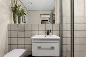 A modern bathroom with a white sink, two bottles of shampoo, and a toilet. - Dolce Vita | Stylish Sea Point Gem (Cape Town)