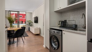 A compact kitchen with a washing machine, a microwave, and a sink. - Dolce Vita | Stylish Sea Point Gem (Cape Town)