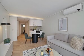 A modern living room with a grey sofa, a coffee table, and a dining area with a white table and chairs. - Dolce Vita | Designer Sea Point Apartment (Cape Town)