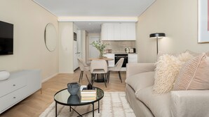 Uma sala de estar moderna com sofá, mesa de centro e área de jantar com cadeiras e uma mesa.