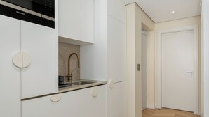 Uma cozinha moderna com armários brancos, uma pia de aço inoxidável e uma lava-louças Siemens.