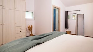Een slaapkamer met een bed, een kledingkast, een raam en een deur.