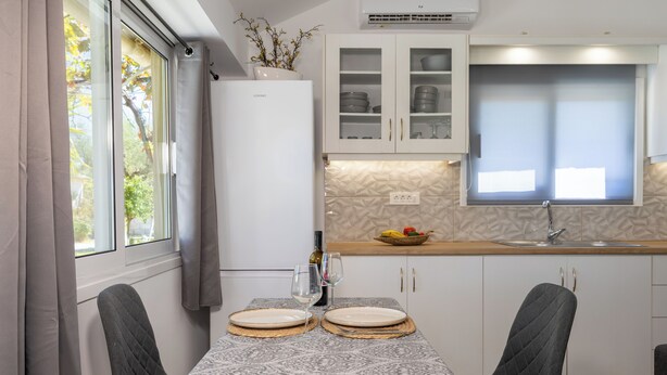 Een moderne keuken met witte kasten, een inbouwoven en een raam met gordijnen.