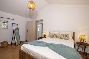 A bedroom with a bed, bedside lamps, a mirror, and a wicker basket. - Destiny s Village II (Zakynthos)
