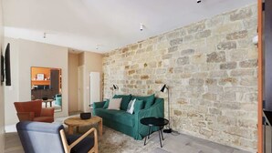 Ein Wohnzimmer mit einer Steinwand, einem grünen Sofa, einem Holztisch und einem blauen Sessel.