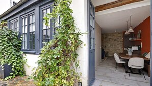 Ein gemütliches Zimmer mit Steinwand, Holzboden und einer Essecke mit Tisch und Stühlen.