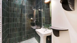 Ein modernes Badezimmer mit Duschkabine aus Glas, einem weißen Waschbecken und einem schwarzen Regal.