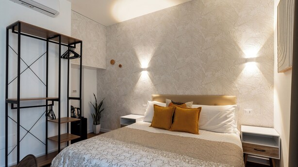 Une chambre moderne comprenant un lit, des tables de chevet, une armoire et un portant à vêtements.