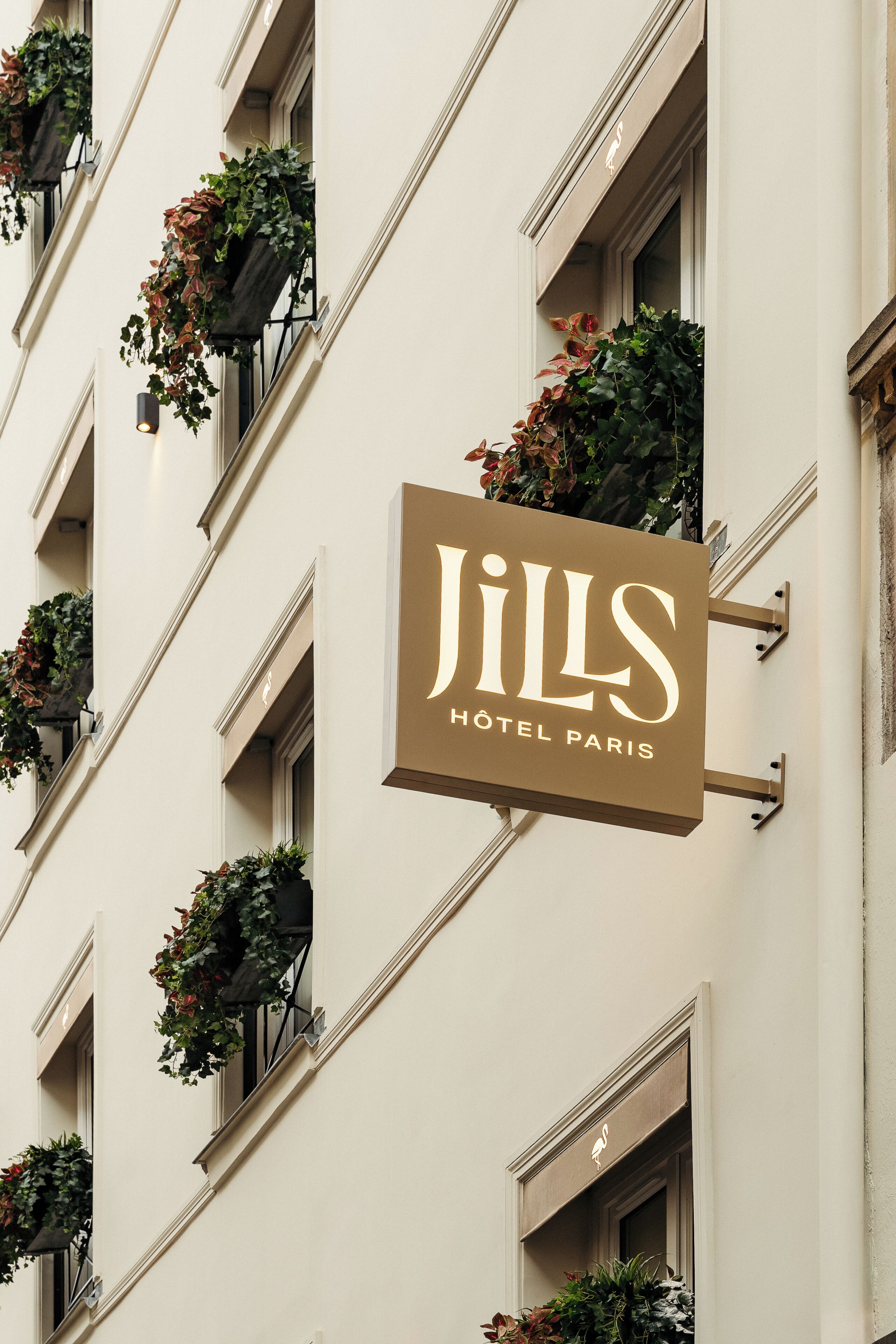 A building with a sign reading 'Jills Hotel Paris' and multiple windows with hanging planters.