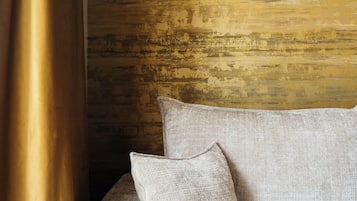 A room with a textured wall, a sofa with pillows, and a wall-mounted light fixture.