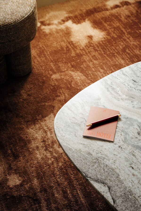 A marble table with a notebook and pen, and a brown carpeted floor. - Jills Hotel (Paris)