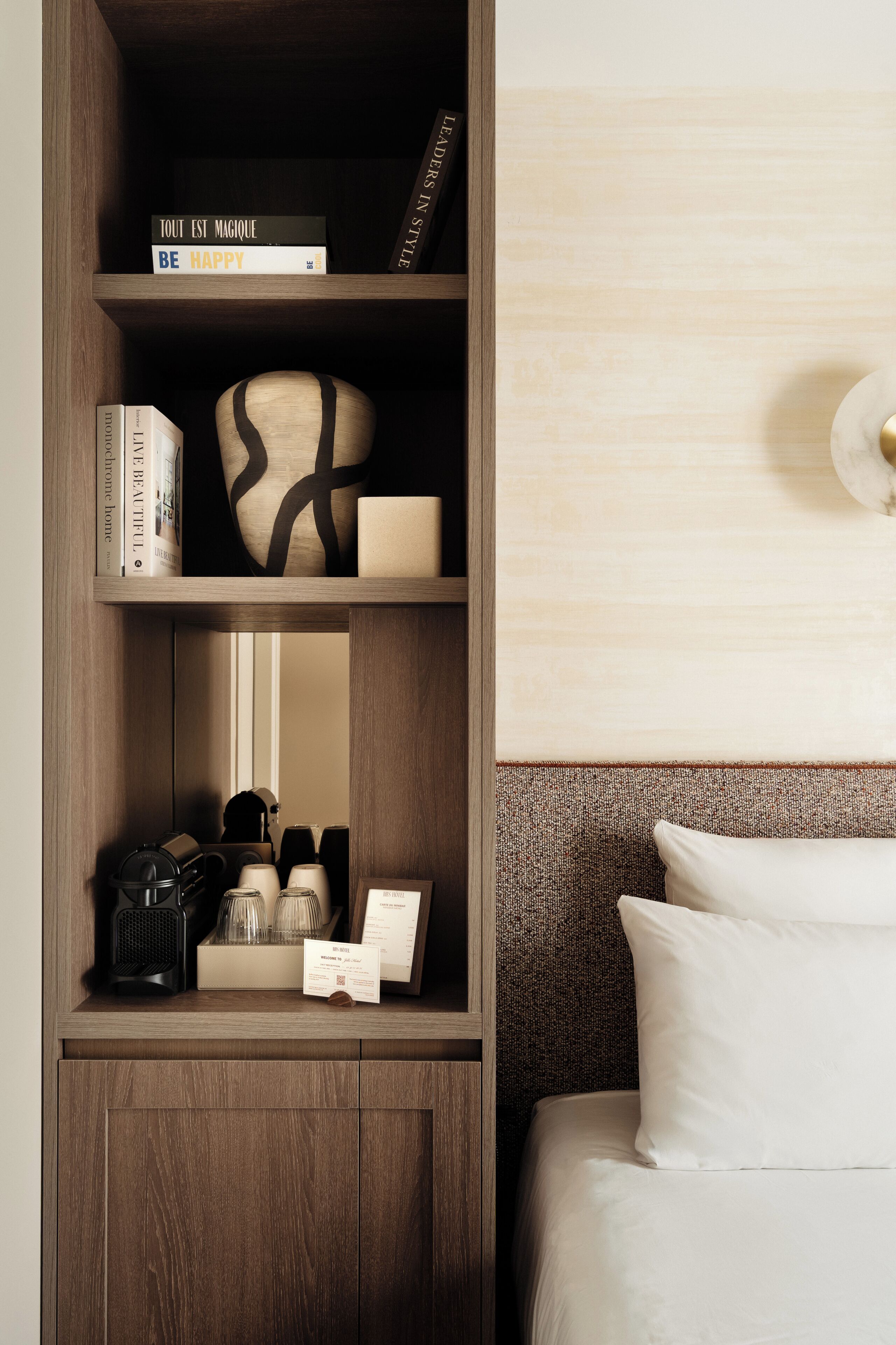 Ein Holzregal mit Büchern, einer Dekovase und einer Kaffeemaschine.