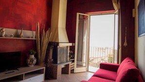 Una sala de estar con pared roja, chimenea, sofá rojo y televisor.