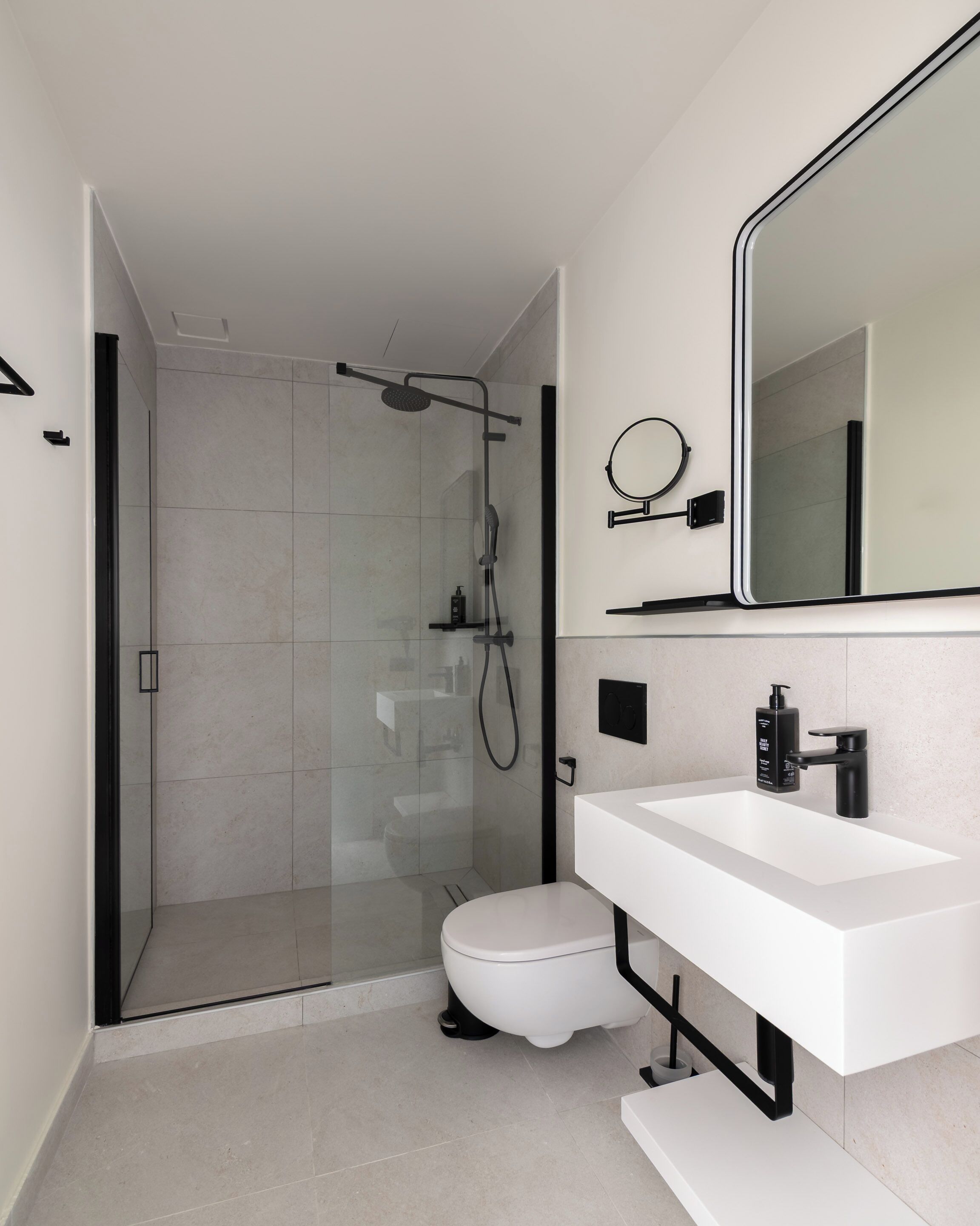 A modern bathroom with a glass-enclosed shower, a white toilet, and a large mirror above a white sink.