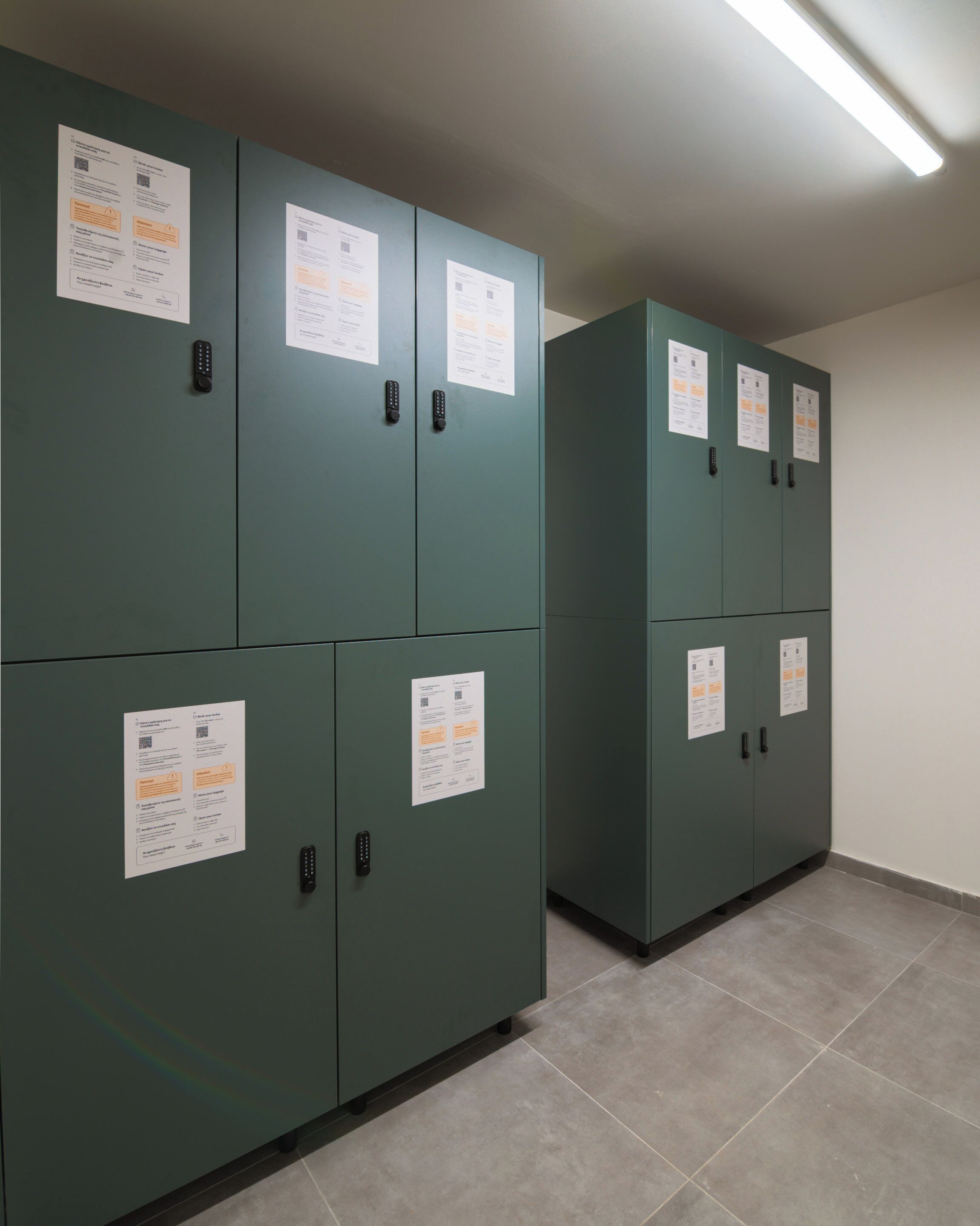A row of green utility cabinets with control panels and informational posters.