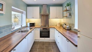 Een moderne keuken met witte kastjes, een ingebouwde oven, een magnetron en een rvs-afzuigkap.