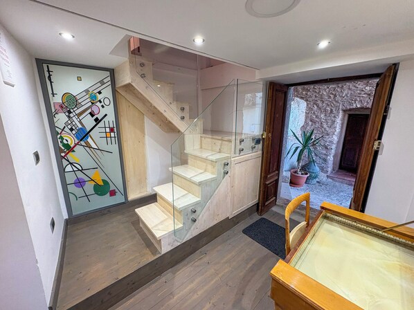 A modern interior with a staircase, a glass door with abstract art, and a wooden table. - B&B StudioArcodia - Sant'Andrea (San Marco d'Alunzio)