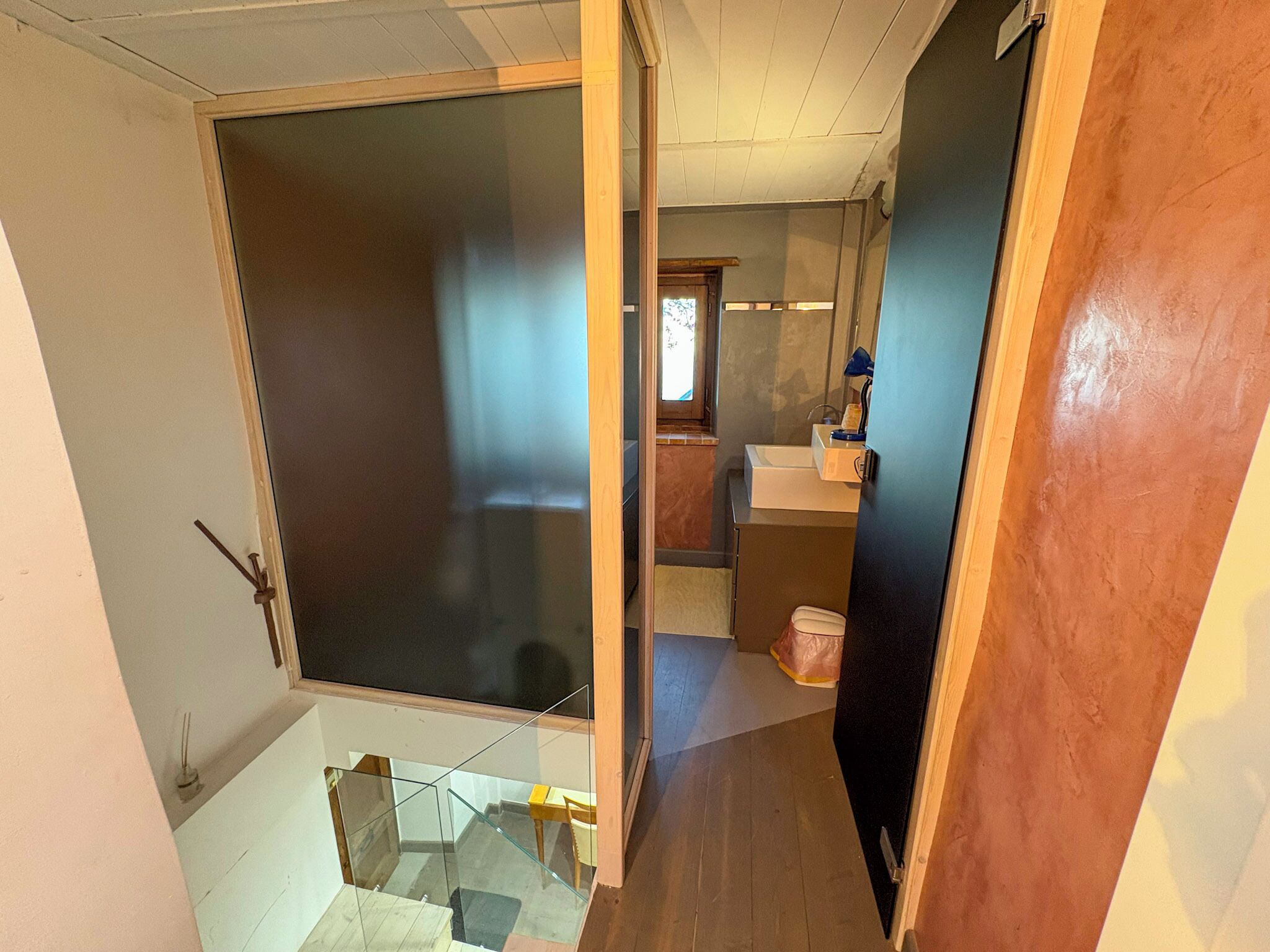 Un couloir étroit avec une porte en verre donnant sur une salle de bain.