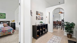 A spacious room with a bed, a black shelving unit, and a dining area with a table and chairs. - Sunshine Serenity Villa (Kissimmee)