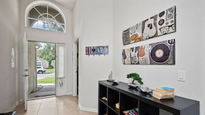 A hallway with a black console table, a small bonsai tree, and wall art. - Sunshine Serenity Villa (Kissimmee)