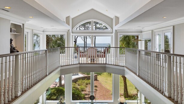 A spacious upper-level balcony with a view of the ocean, white railings, and a well-maintained lawn below. - MyStay at 14 Laughing Gull – Premier Oceanfront Estate in Sea Pines (Hilton Head Island)