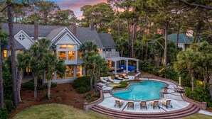 A two-story house with a large backyard featuring a swimming pool, outdoor seating, and a covered patio area. - MyStay at 14 Laughing Gull – Premier Oceanfront Estate in Sea Pines (Hilton Head Island)