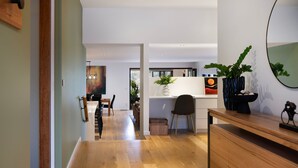 Una cucina moderna con pavimento in legno, una zona pranzo con tavolo e sedie, e un'ampia finestra.