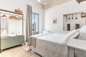 A bedroom with a bed, a dresser, a window with curtains, and a wall-mounted shelf with a basket. - Borgo Altobello (Cisternino)