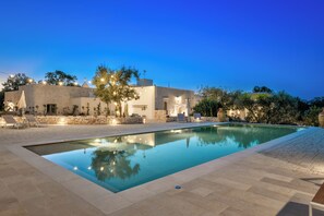 A swimming pool with lounge chairs and a stone wall. - Borgo Altobello (Cisternino)
