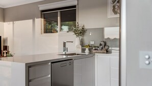 Una cocina moderna con lavavajillas, una ventana sobre el fregadero y un florero con flores en la encimera.