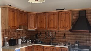 A kitchen with wooden cabinets, a stove, and a hanging light fixture. - Tirana • 2 Single Beds • Free Wi-Fi • Pet-Friendly • Shared Kitchen & Bathroom (Tiarana)