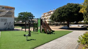 A playground with green artificial turf, a slide, and climbing structures. - Laguna Green Apartment (El Morche)