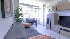 A modern living room with a sofa, TV, and dining area. - Laguna Green Apartment (El Morche)